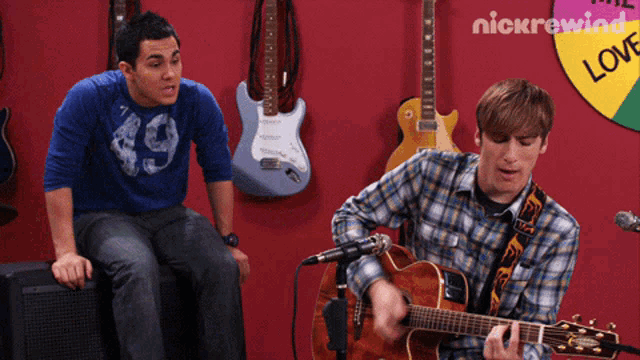 a man playing a guitar in front of a sign that says nick rewind