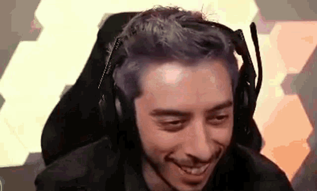 a man with purple hair is wearing a headset and smiling .