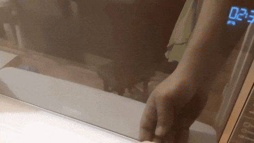a person is using a microwave with a digital display showing the time as 07:23