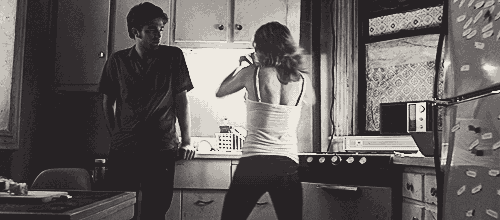 a black and white photo of a man and woman in a kitchen