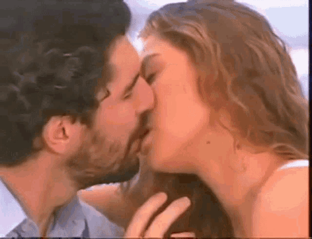 a man and a woman are kissing in front of a beach .
