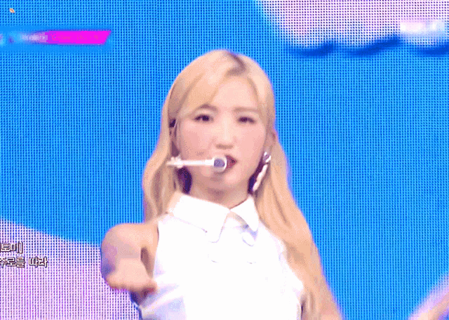 a blonde woman with a microphone in her mouth stands in front of a blue background