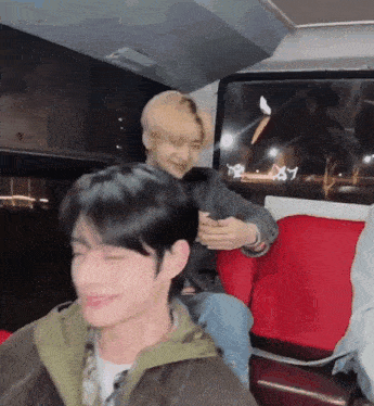 a group of young men are sitting on a red bus .