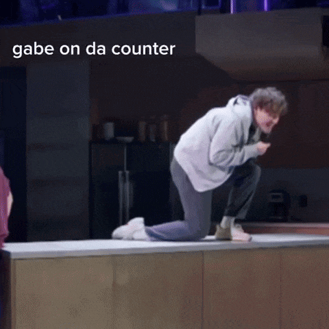 a man is kneeling on a counter with the words gabe on da counter above him .