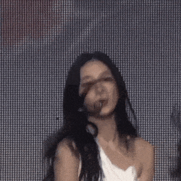 a woman is standing on a stage in front of a screen and looking at the camera .