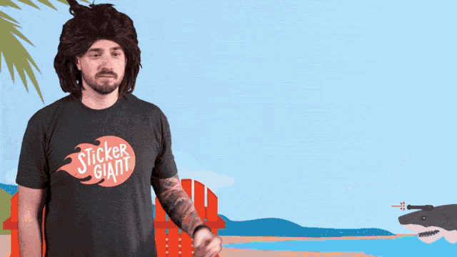 a man wearing a sticker giant shirt points to a shark on the beach