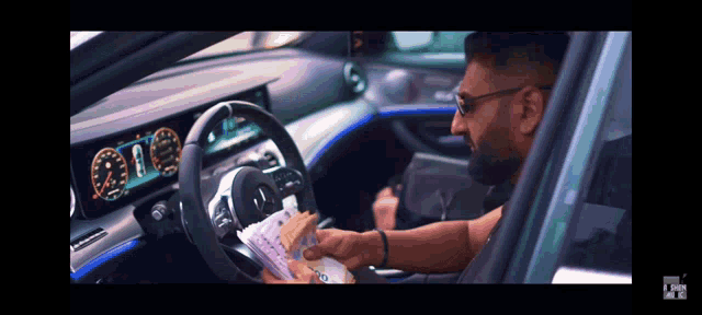 a man in a car holds a bunch of money in his hand
