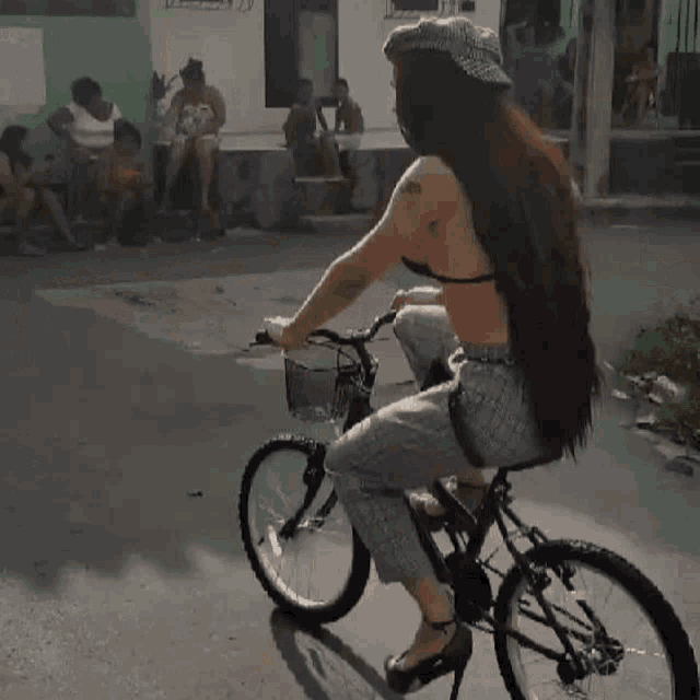 a woman is riding a bike down a street while a little girl stands next to her