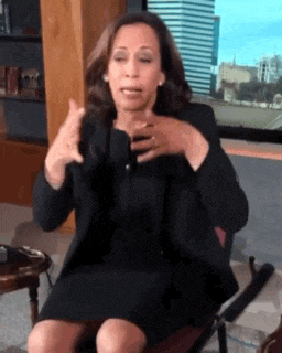 a woman in a black dress is sitting in a chair making a gesture