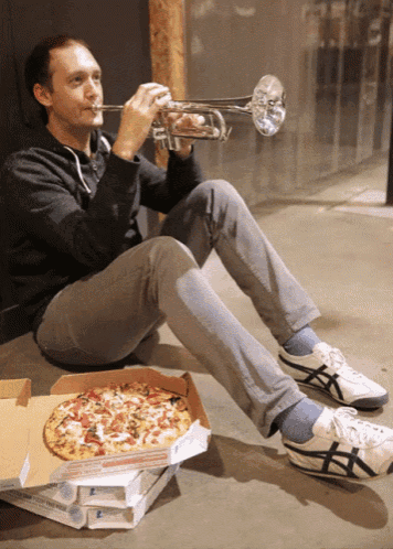a man playing a trumpet next to a pizza box