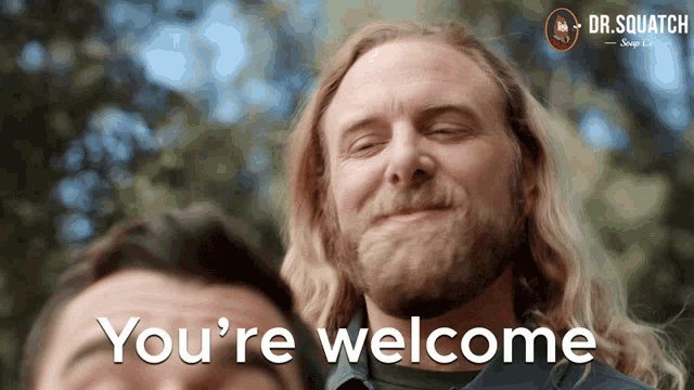 a man with a beard is smiling with the words you 're welcome behind him