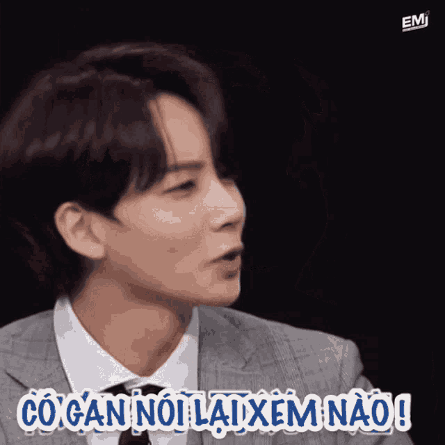 a man in a suit and tie is making a funny face and says " co gan noi lai xem nao "