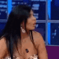 a woman wearing a plunging top and earrings is sitting on a couch .