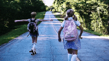 a boy rollerblading down a road next to a girl rollerblading down the road .