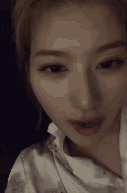 a close up of a woman 's face with a white shirt on