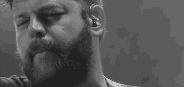 a close up of a man with a beard wearing ear buds .