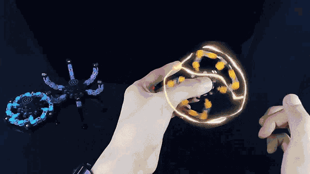 a person is playing with a fidget spinner that looks like a spider with glowing eyes
