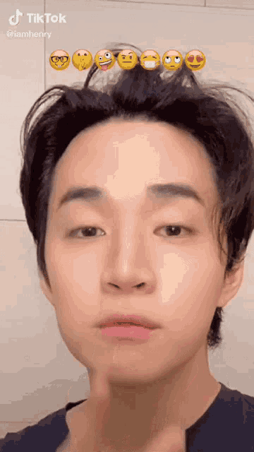 a young man with a lot of emojis on his head is making a funny face .