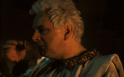 a man with white hair and a gold collar is holding something in his hand