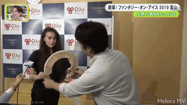 a woman is being interviewed by a man in front of a wall that says ' 50th ' on it