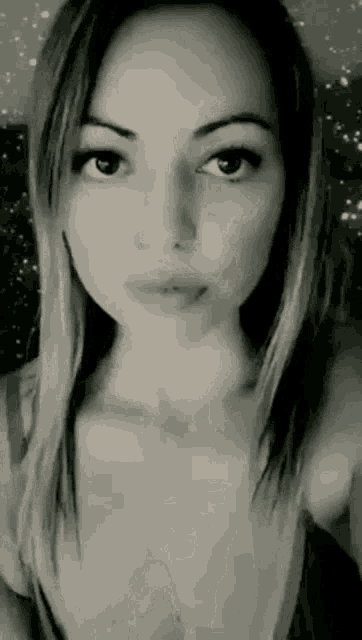 a black and white photo of a woman taking a selfie with a starry background .