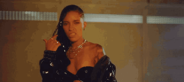 a woman with a shaved head is wearing a black jacket and a necklace