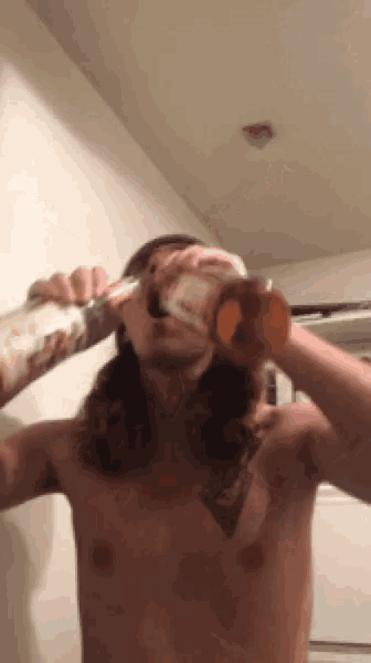 a shirtless man drinking from a bottle with his mouth open