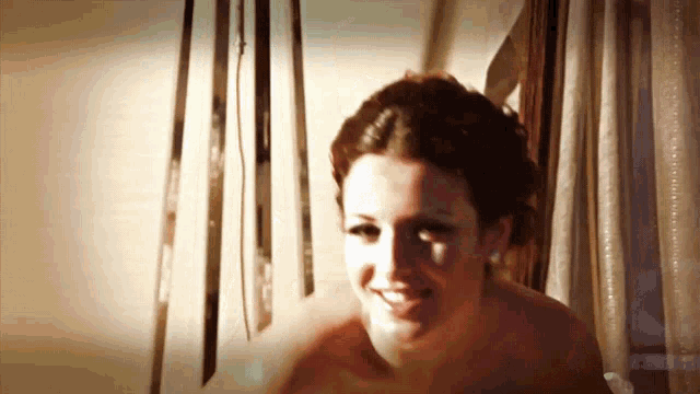 a woman without a shirt is smiling in a room