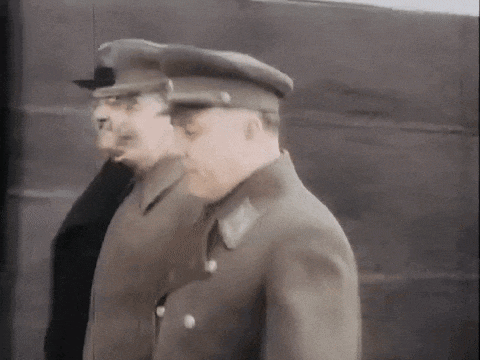 two men in military uniforms are standing next to each other in front of a wall .