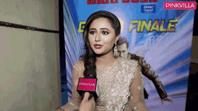 a woman talking into a microphone in front of a poster that says finale
