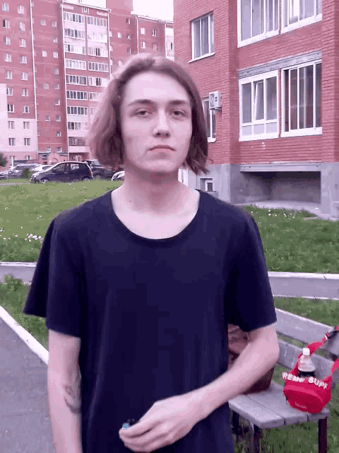 a young man wearing a black t-shirt with the word supreme on it stands in front of a brick building