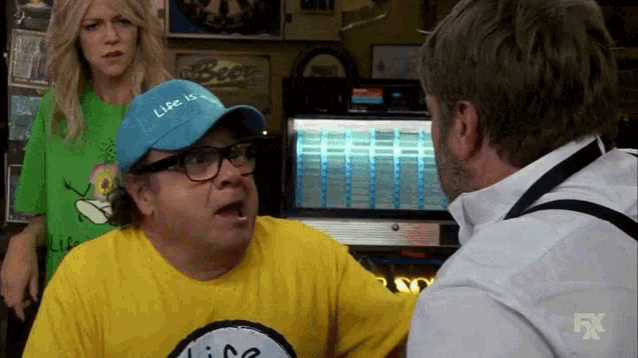 a man wearing a blue hat with the word life on it is talking to another man .