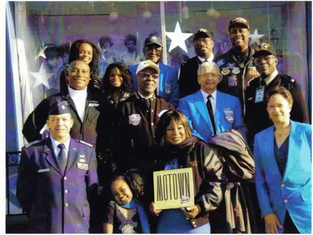 a group of people are posing for a picture and one of them is holding a sign that says motown