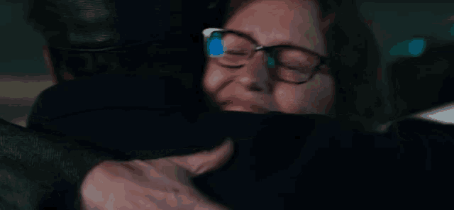 a woman with glasses is hugging a man in a car .