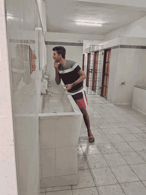 a man brushing his teeth in a bathroom while wearing a shirt that says ' abercrombie & fitch '