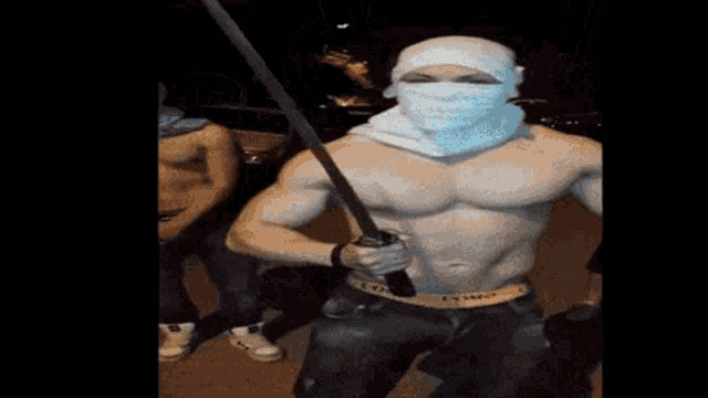 a shirtless man holding a sword with a bandana on his face
