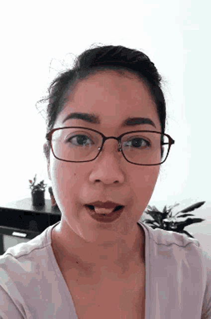 a woman wearing glasses and a purple shirt looks at the camera