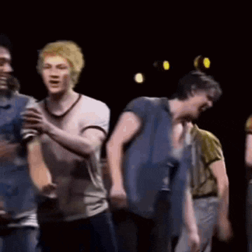 a group of young men are dancing together on a stage in a dark room .