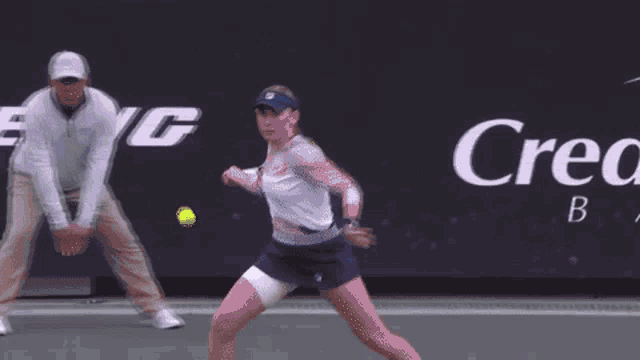 a woman is playing tennis in front of a banner for credit one bank