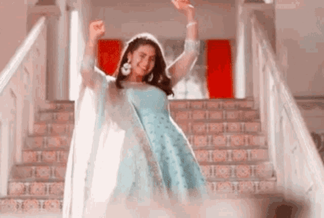 a woman in a blue dress is dancing on the stairs .