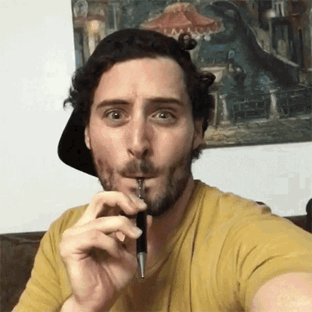a man with a beard is smoking an electronic cigarette while wearing a hat .
