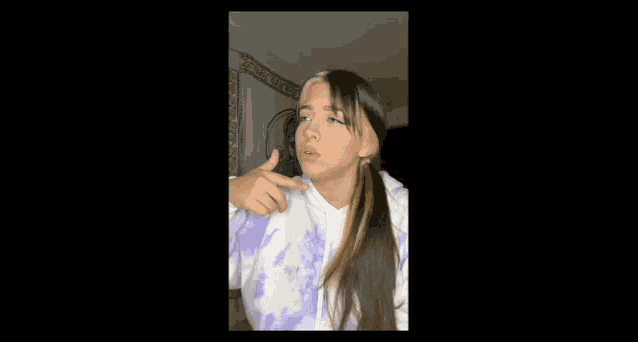 a girl in a purple and white tie dye sweatshirt is making a funny face