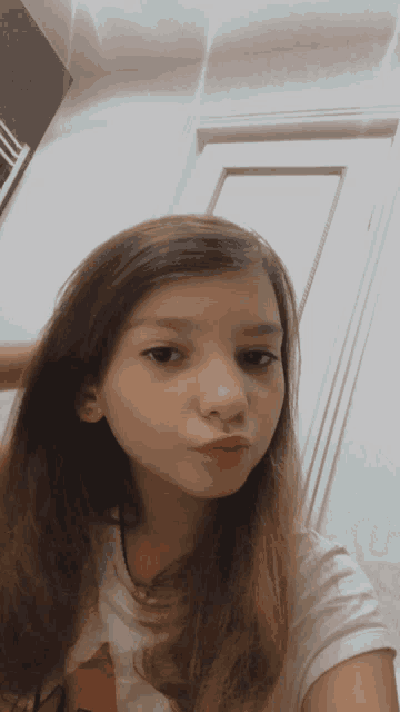 a young girl with long brown hair is taking a selfie in front of a door