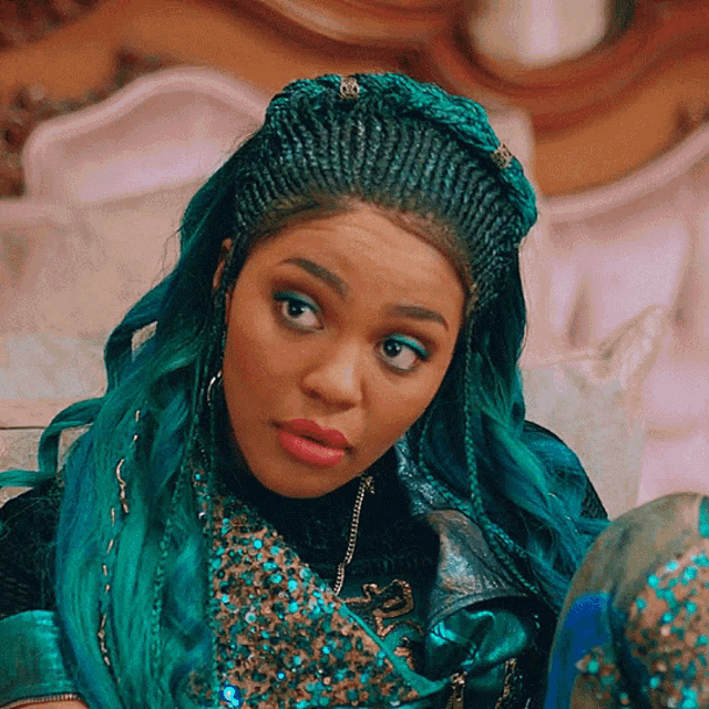 a woman with teal hair and braids is sitting on a bed