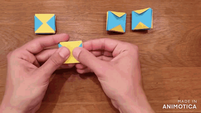 a person is holding a piece of yellow and blue paper that says made in animatica on it