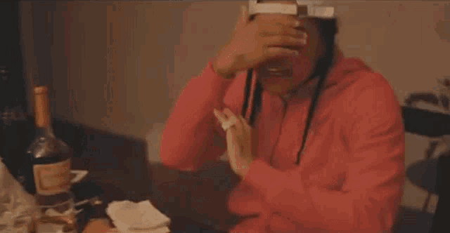 a man is sitting at a table with a bottle of alcohol and a bunch of money .