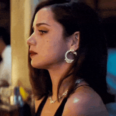 a woman wearing hoop earrings and a necklace is looking down .
