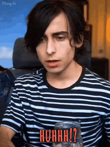 a young man in a striped shirt is sitting in a chair and making a surprised face .