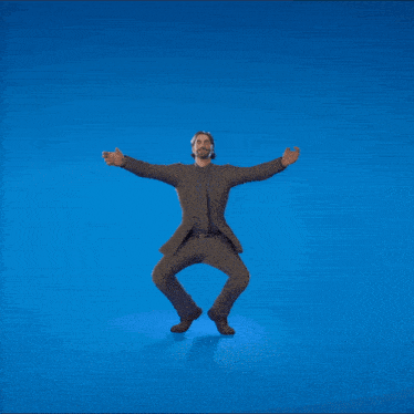 a man in a suit is dancing in front of a blue background