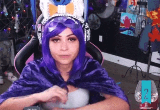 a woman in a purple wig and headphones is sitting in a chair in a room .